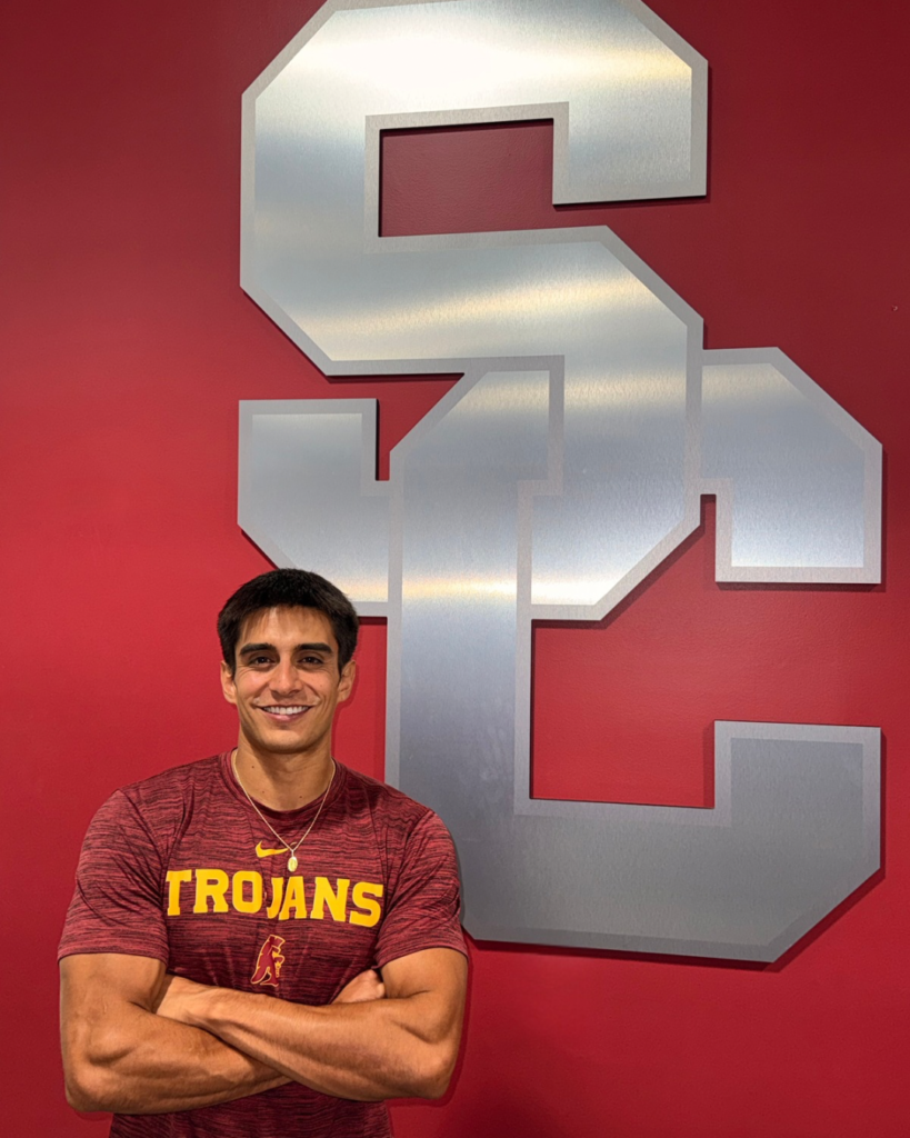 Jason Diaz Jr standing in front of the USC Trojans logo at the University of Southern California Galen Center weight room.